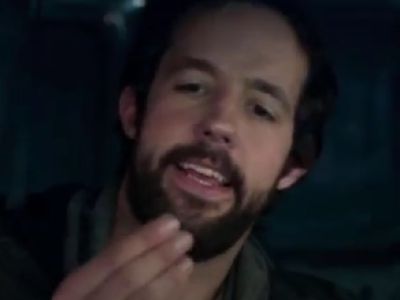 Peter Cambor is holding something in his hand and looking at it.